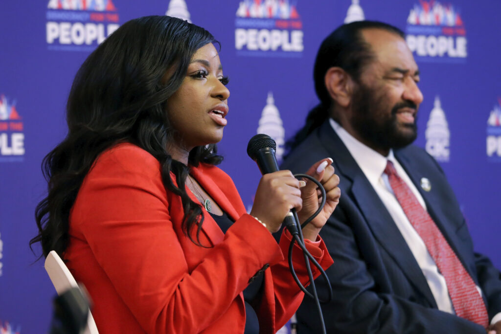 U.S. Rep. Jasmine Crockett, D-Texas, left, speaks as U.S. Rep. Al Green, D-Texas, listens during a race and democracy summit sponsored by the Congressional Black Caucus on July 28, 2023, in Houston. Photo credit: Michael Wyke, The Associated Press